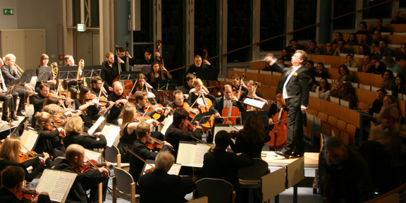 An orchestra plays in a darkened auditorium
