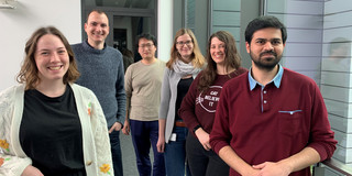 Six people standing in front of a door frame