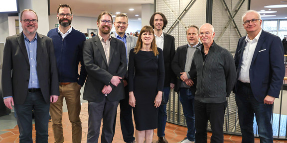 Eröffnung DoBaS Acht Männer und eine Frau posieren gemeinsam für ein Gruppenfoto.