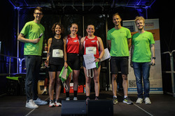 Auf einer Bühne stehen die drei ersten des 10-Kilometer-Laufs mit ihren Urkunden, die zwei Moderatoren und der Leiter des Hochschulsports