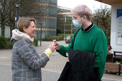 Prof. Wiebke Möhring verteilt einen Kugelschreiber an einen Studenten.