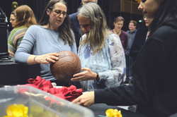 Foto: Mehrere Personen stehen zusammen und betrachten einen historischen Lederfußball zwischen roten und gelben Dekorationselementen.
