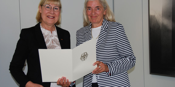 Bundesverdienstkreuz Zwei Frauen, eine hält Urkunde in der Hand