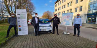 Four men in front of an electric car