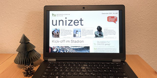 Ein Laptop steht auf einem Tisch und zeigt die digitale Version der neuen unizet Dezember Ausgabe.