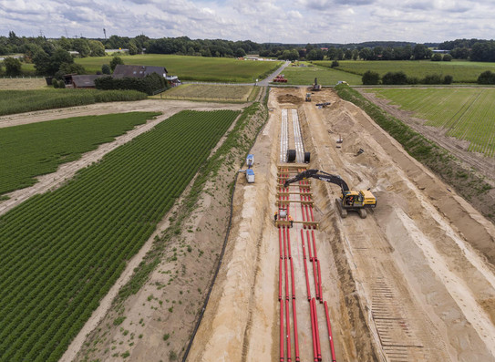 Stromtrasse Eine Stromtrasse wird auf einem Erdboden gebaut und links und rechts sind grüne Felder zu sehen.