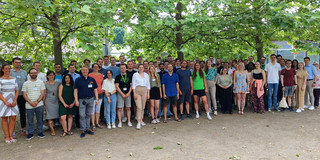 Eine große Gruppe, bestehend aus Studierenden und Lehrenden, posiert für ein Gruppenfoto.