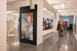 Zwei Personen stehen in einem Ausstellungsraum und schauen sich Gemälde an.