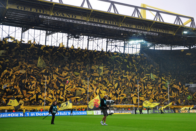 Football fans dressed in yellow and black jerseys in a football stadium