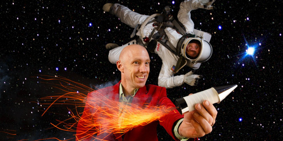 Two men, one in red suit and one in space suit in front of starry background