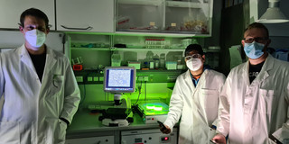 A man on the left and a woman and a man on the right in the lab wearing white coats.