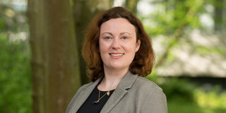 Zu sehen ist ein Portraitfoto von Prof. Anna Isaeva mit Bäumen im Hintergrund