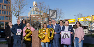 Foto: Eine Gruppe von Personen steht mit goldenen Ballons und Plakaten im Stadtzentrum von Dortmund.
