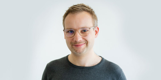 Portrait photo of Prof. René Westerholt in front of a light background: Prof. Westerholt is wearing glasses and a dark top.