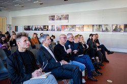 Dozentinnen und Dozenten der Hochschulen sitzen in der ersten Reihe des Publikums. Sie und die Studierenden hinter ihnen schauen nach vorne. Apl. Prof. Olaf Schmidt hält ein Mikrofon und spricht.