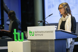 Eine Frau hält an einer Kanzel mit TU-Logo eine Rede