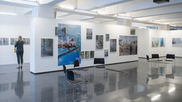 Ein Foto von einem Ausstellungsraum mit weißen Wänden und vielen Fotografien.
