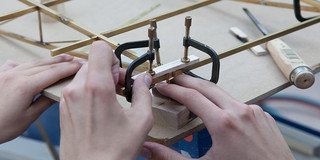 Detailaufnahme von Händen, die einen Winkel in einem Holzmodell messen.