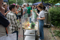 mehrere Menschen stehen um einen kleinen Stand herum