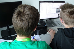 Zwei Teilnehmer entwickeln am PC einen Quellcode. 