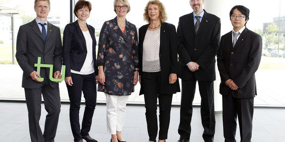 Group photo with three men and three women standing in front of a window frontage