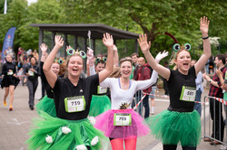 Kostümierte Läuferinnen beim Campuslauf, die jubelnd die Arme heben