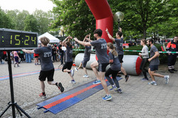 Einige Teilnehmende des Campuslauf laufen jubelnd über die Ziellinie.