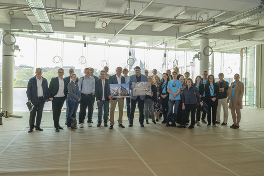 Foto: 27 Personen, darunter Prof. Manfred Bayer, stehen für ein Gruppenfoto im Rohbau zusammen.