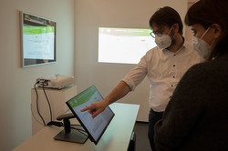 Interaktive Bildschirme in der Ausstellung Zwei Personen stehen an einem interaktiven Bildschirm