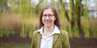 A portrait photo of a woman with glasses and a white blouse on the TU Dortmund campus.