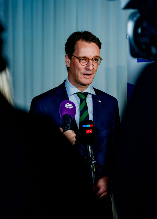 Foto: Ministerpräsident Hendrik Wüst in eiem Anzug. Wüst gibt Journalisten ein Interview und spricht in ein Mikrofon.