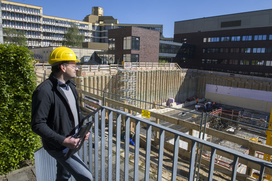 Ein Mann mit Schutzhelm schaut auf eine Baustelle.