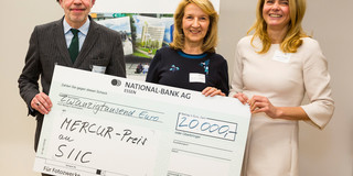 MERCUR Förderpreis Ein Mann und zwei Frauen halten einen übergroßen Scheck in den Händen.