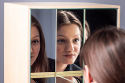 Eine Fraut schaut in einen Holzkasten mit Spiegeln