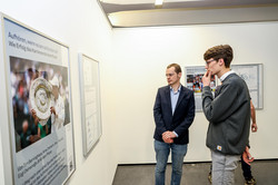 Zwei Personen stehen vor einem Poster in einer Ausstellung