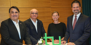 Gruppenfoto: Vier Personen um einen runden Tisch beim Gambrinus-Forum, mit sichtbar platziertem TU Dortmund-Logo auf dem Tisch.