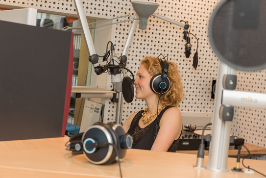 Student smiles at the microphone during the recording in the Eldoradio studio