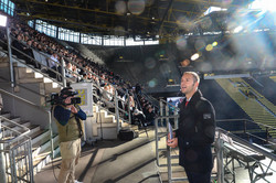 Christoph Edeler steht vor vielen jungen Leuten auf einer Tribüne im Signal-Iduna-Park.