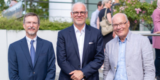 Three men in suits pose side by side for a photo.