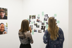 Fotofestival f² Zwei Besucherinnen betrachten eine Installation aus Fotos und Texten.