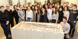Gruppenfoto mit Modellentwurf aus Holz im Vordergrund
