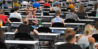 Viele Studierende sitzen mit Abstand zueinander an Tischen.