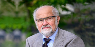 Ein Porträtbild eines Mannes vor grünem Hintergrund, der Mann ist Nobelpreisträger Erwin Neher.