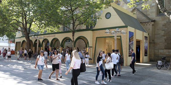 Stadt Paradies Sanktreinoldi Menschen laufen im Vordergrund an der Reinoldikirche im Hintergrund vorbei.