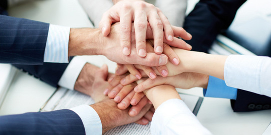 Close up of nine hands lying on top of each other