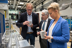 Prof. A. Erman Tekkaya, Ina Brandes und Albrecht Ehlers betrachten zylinderförmige Objekte. 