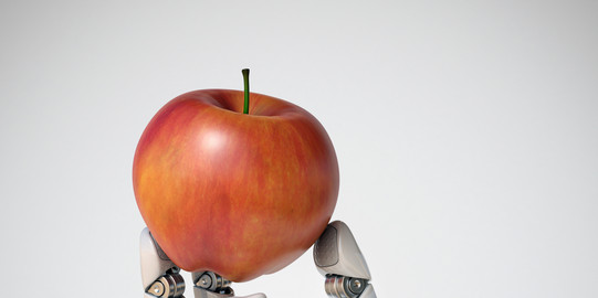 A robot's arm is holding an apple