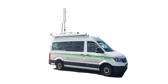 Mobiles 5G-Labor Ein Lieferwagen, der mit einer Antenne auf dem Dach ausgestattet ist und auf dem das Logo der TU Dortmund zu sehen ist.