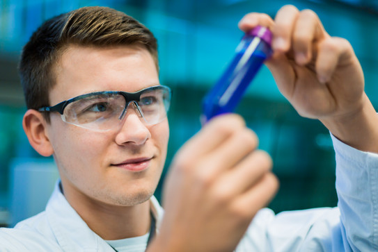 Auszubildender im Chemielabor mit Probengefäß Auszubildender im Chemielabor mit Probengefäß