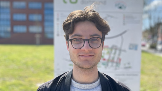 Portrait vom Studenten Rafael Reis vor einem Schild der TU Dortmund